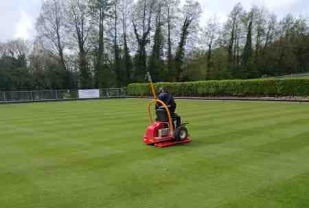 man on heavy roller, flattening the green